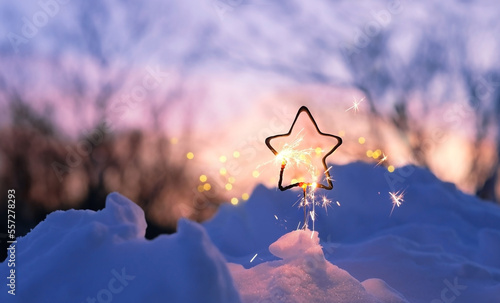 burning sparkler in snow, winter natural abstract background. Christmas and new year holidays. festive winter season. dreams, fantasy, romantic atmosphere image. sparkler of star shape