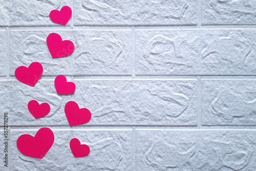 Pink hearts on white brick wall background. Top view. Paper cutting. Copyspace. Romantic home decor for lovers. Flatlay. Concept of preparing for Valentine's Day. Space for text. photo