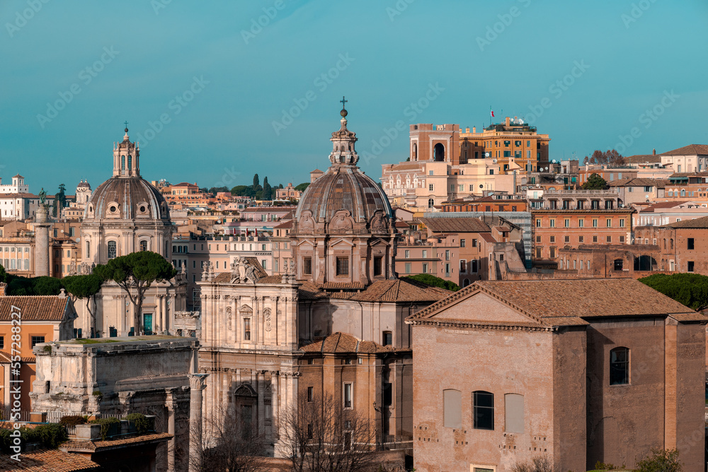 The beautiful orange and blue skyline of the historical city of Italian Rome shows European urban architecture - basilicas, monuments, towers, buildings, and baroque temples noticeable by its cupolas.