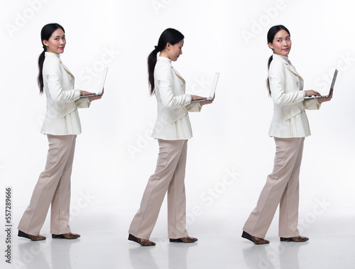 Full length 20s Asian Woman wear formal business blazer suit dress pant shoes. Black long straight hair female hold laptop work confident, walk forward turn left right, white background isolated