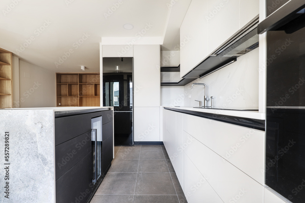 A newly installed modern kitchen with off-white handleless cabinets, steel faucets and an island with a wine fridge A newly installed modern kitchen with off-white handleless cabinets, steel faucets and an island with a wine fridge