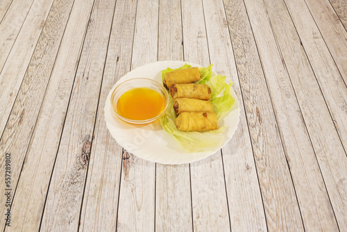 Small fried Thai spring rolls on a lettuce leaf and with dipping sauce