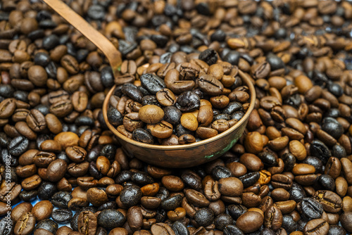 closeup of a copper bowl over a pile of roasted coffee beans