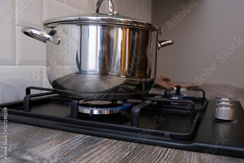 Burning gas burner with blue flames on kitchen black gas stove with a bokeh effect. steel pot