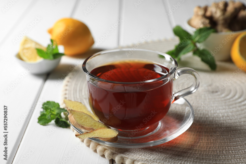 Cup of delicious ginger tea and ingredients on white wooden table Cup of delicious ginger tea and ingredients on white wooden table