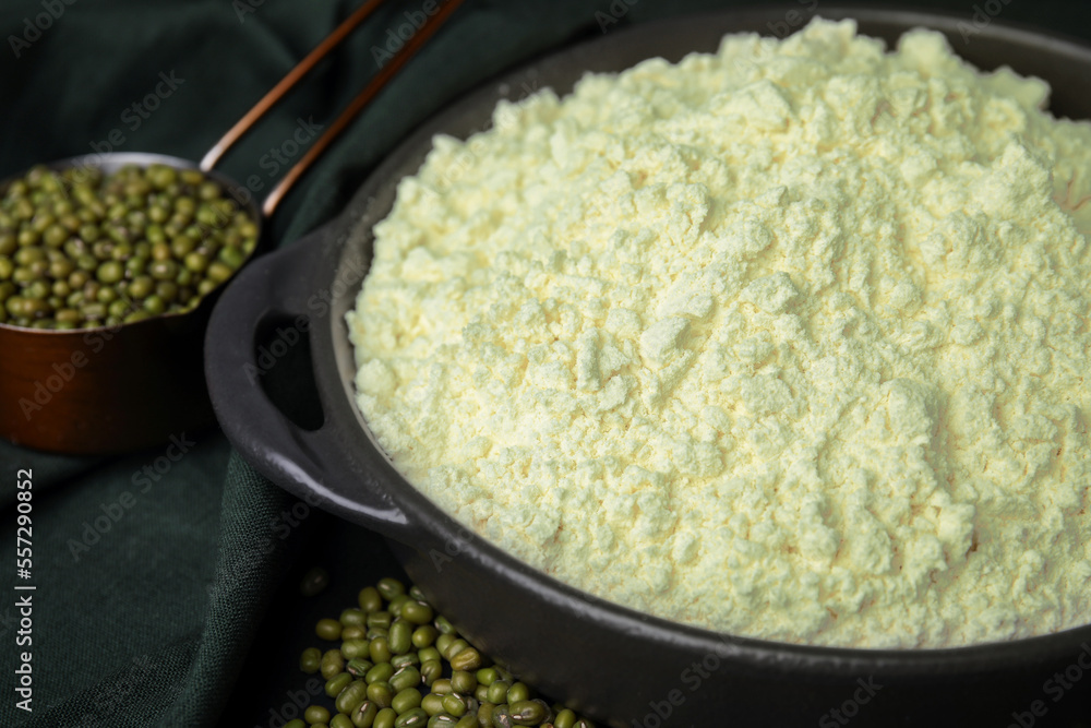 Pan with flour and mung beans on black background, closeup