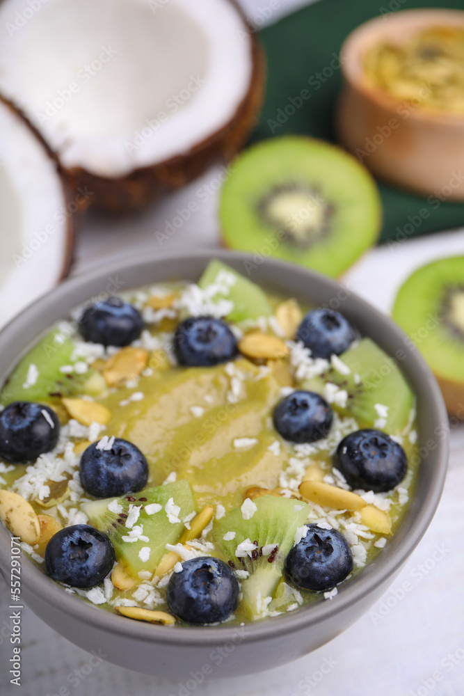 Bowl of delicious fruit smoothie with fresh blueberries, kiwi slices and coconut flakes on white wooden table, closeup Bowl of delicious fruit smoothie with fresh blueberries, kiwi slices and coconut flakes on white wooden table, closeup
