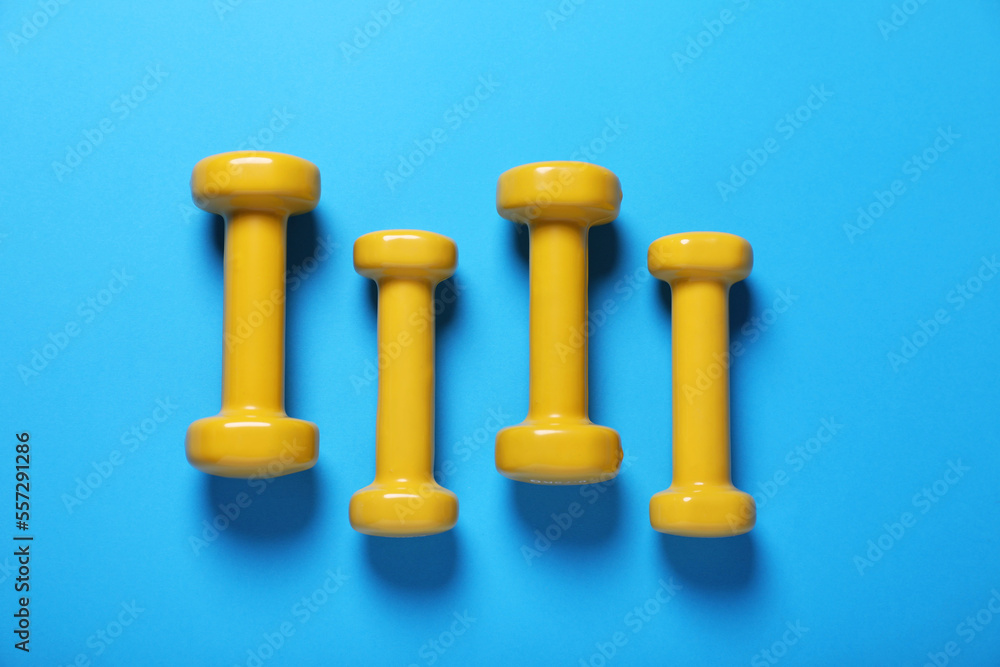 Yellow dumbbells on light blue background, flat lay. Morning exercise Yellow dumbbells on light blue background, flat lay. Morning exercise