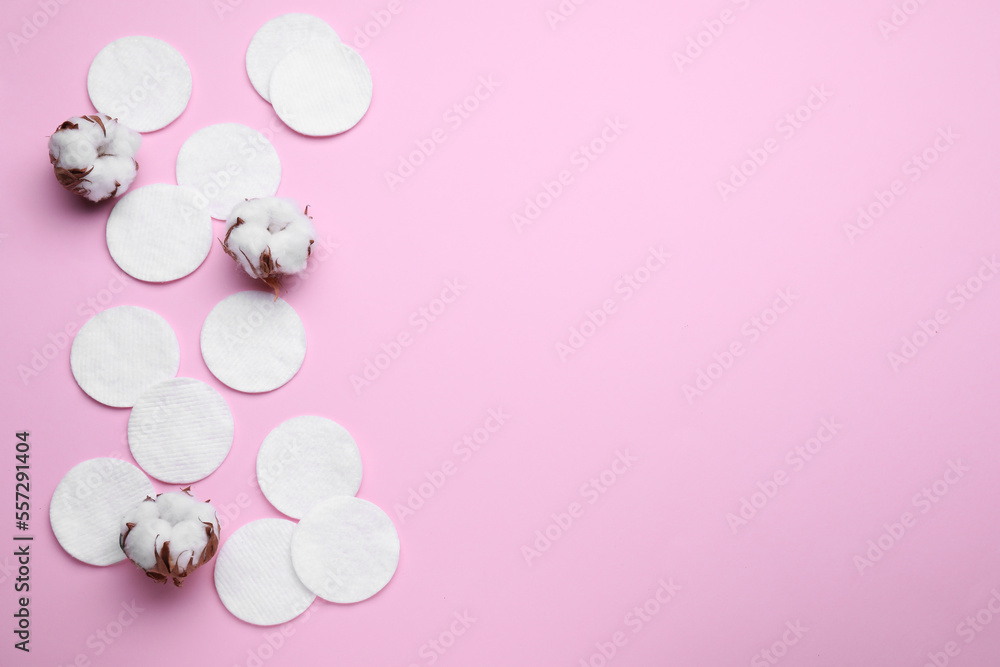 Soft clean cotton pads and flowers on pink background, flat lay. Space for text