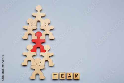 Red figure among wooden ones and cubes with word Team on light grey background, flat lay with space for text. Recruiter searching employee