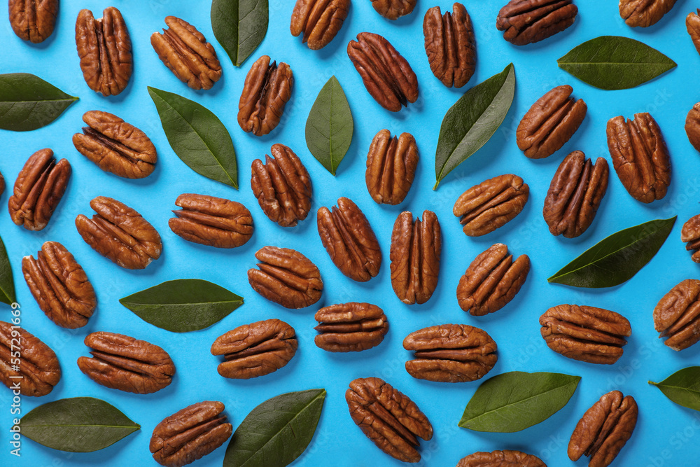 Flat lay composition with tasty pecan nuts and green leaves on light blue background Flat lay composition with tasty pecan nuts and green leaves on light blue background