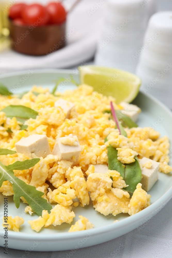 Delicious scrambled eggs with tofu and lime served on white table, closeup
