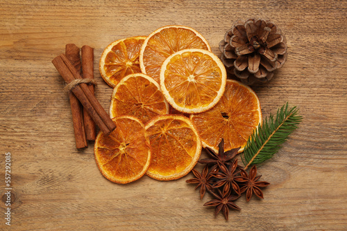Dry orange slices, cinnamon sticks, fir branch and anise stars on wooden table, flat lay