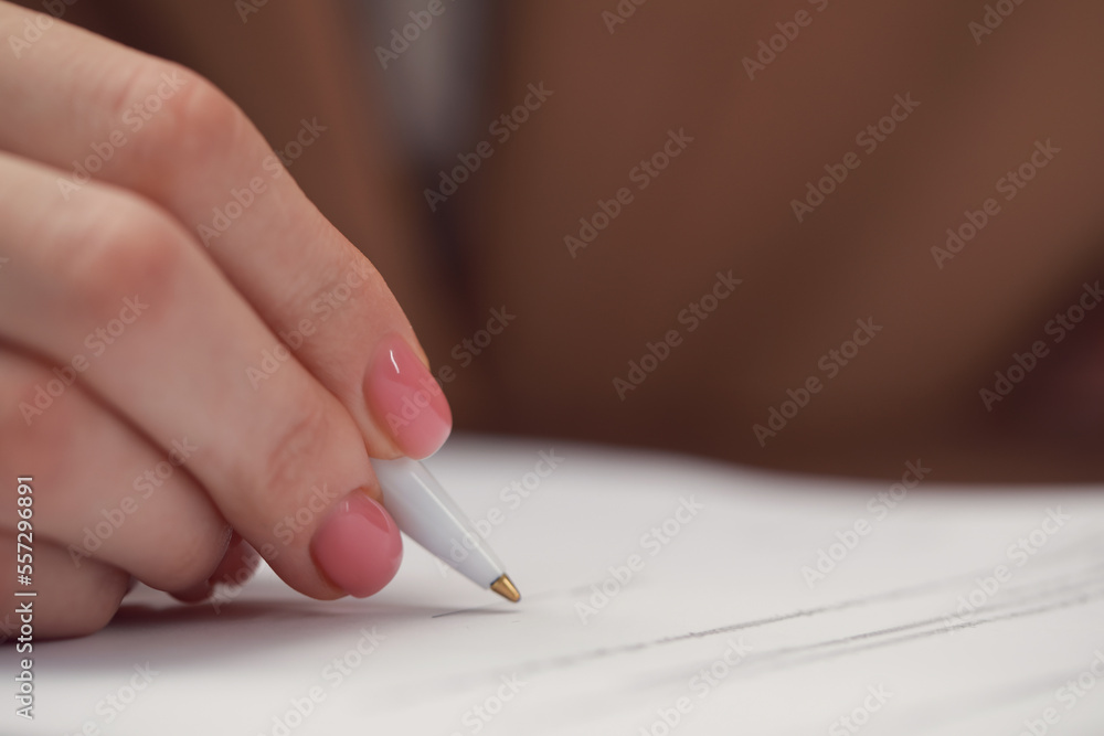 Woman signing documents at table in office, closeup. Space for text Woman signing documents at table in office, closeup. Space for text