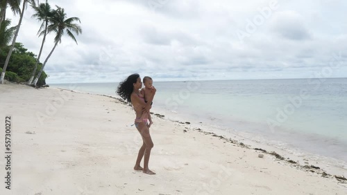 Mom and baby having fun dancing on beach on vacation. A Filipino mother with her mestizo son in her arms spins on the beach while relaxing in the tropics. Life and development of a child in tropics