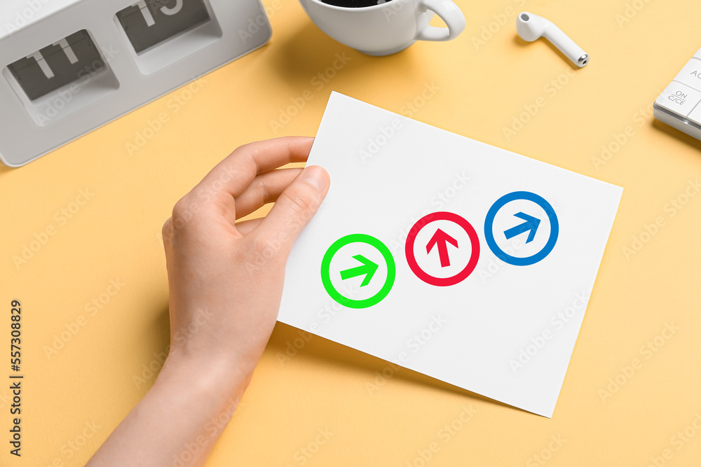 Woman holding paper sheet with drawn arrows at office table, closeup. Concept of choice Woman holding paper sheet with drawn arrows at office table, closeup. Concept of choice