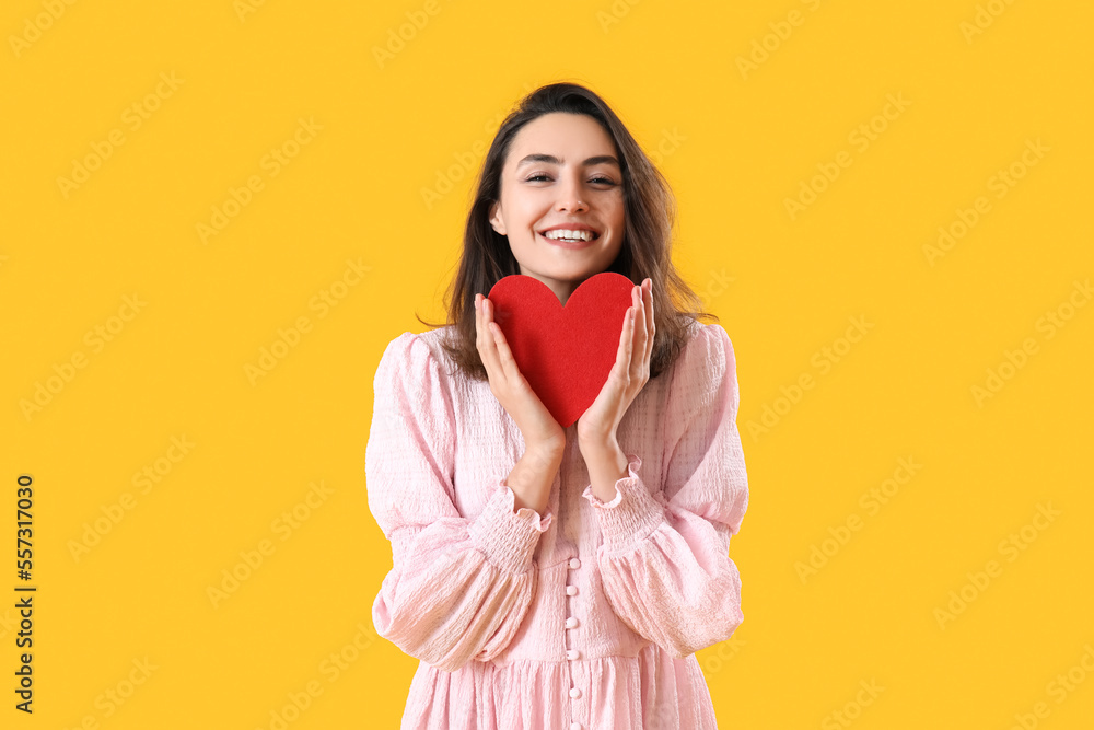 Young woman with paper heart on yellow background. Valentine's Day celebration Young woman with paper heart on yellow background. Valentine's Day celebration
