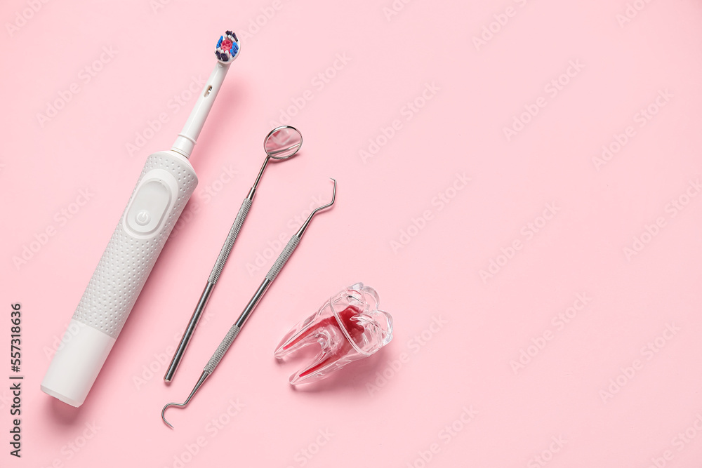 Plastic tooth with dental tools and electric brush on pink background Plastic tooth with dental tools and electric brush on pink background