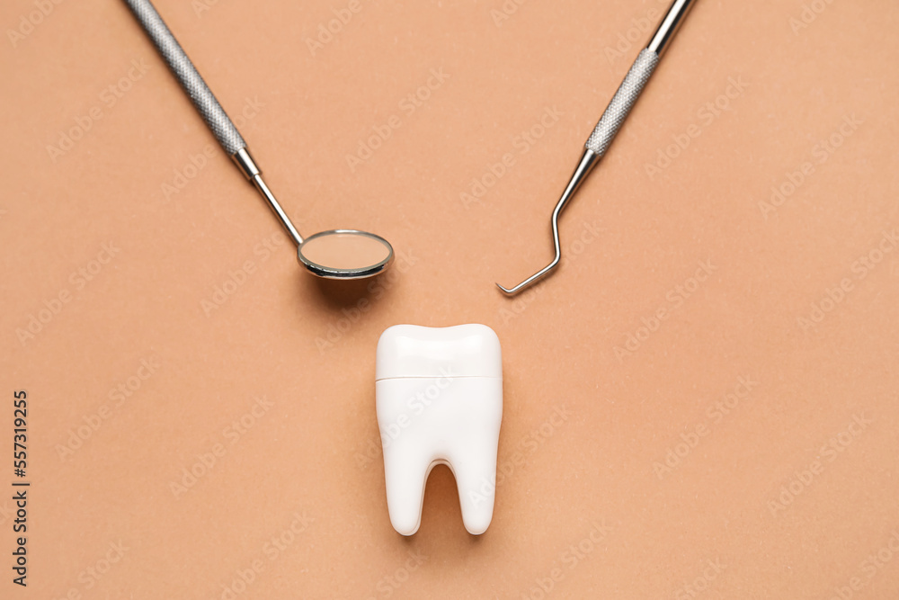 Plastic tooth with dental tools on brown background - obrazy, fototapety, plakaty 