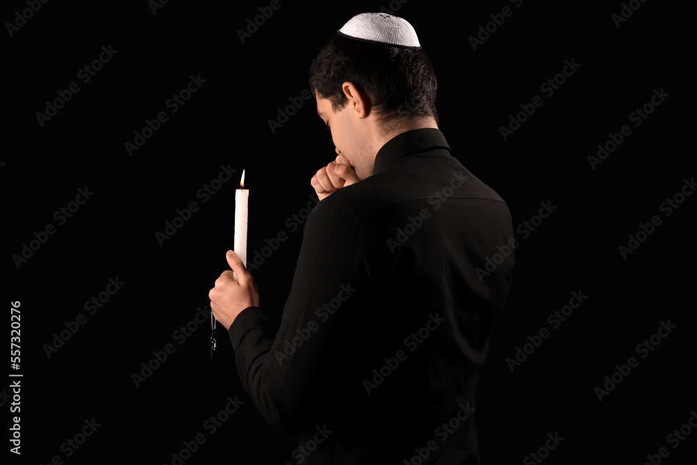 Praying Jewish man with candle on dark background. International Holocaust Remembrance Day Praying Jewish man with candle on dark background. International Holocaust Remembrance Day
