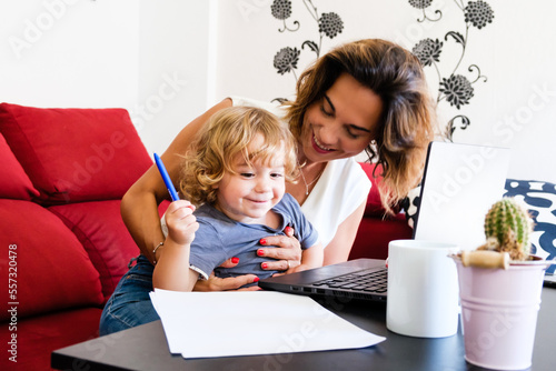 Smiling single mother works from home with her young son. photo