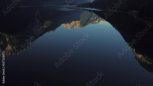 Reflection of rocky mountains on surface of alpine lake, tilt up and reveal of beautiful valley. Lago Del Predil, Italy, Europe. Drone aerial push in, tilt up and reveal. photo