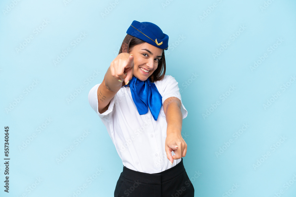 Airplane stewardess caucasian woman isolated on blue background points finger at you while smiling Airplane stewardess caucasian woman isolated on blue background points finger at you while smiling