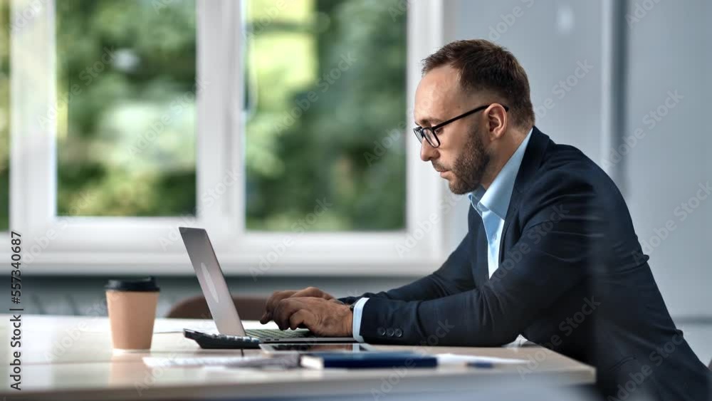 Success male boss CEO executive employee browsing internet chatting use laptop at office desk window Success male boss CEO executive employee browsing internet chatting use laptop at office desk window