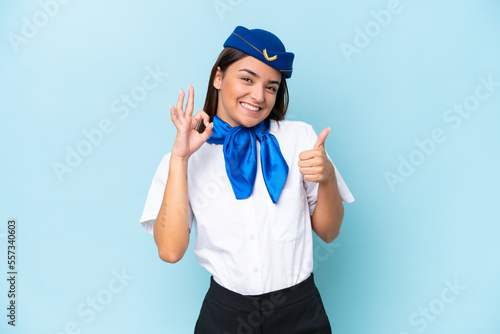 Airplane stewardess caucasian woman isolated on blue background showing ok sign and thumb up gesture