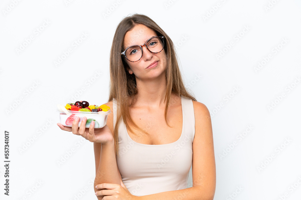 Young pretty woman holding a bowl of fruit isolated on white background with sad expression