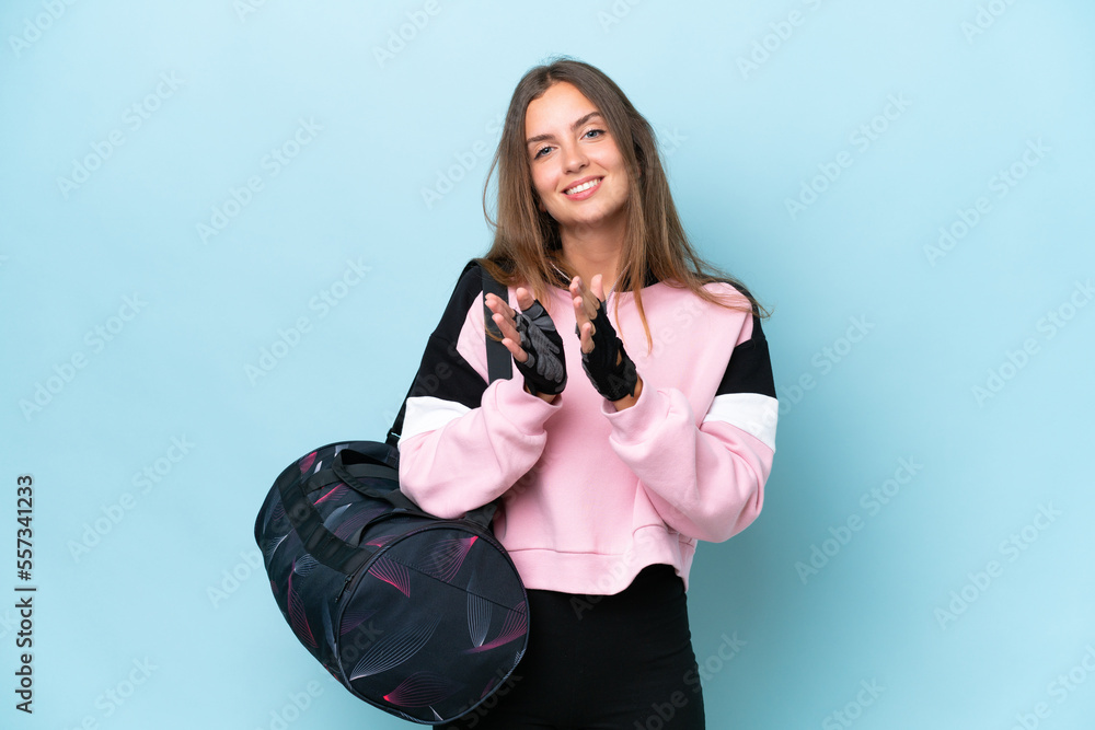 Young sport woman with sport bag isolated on blue background applauding after presentation in a conference Young sport woman with sport bag isolated on blue background applauding after presentation in a conference