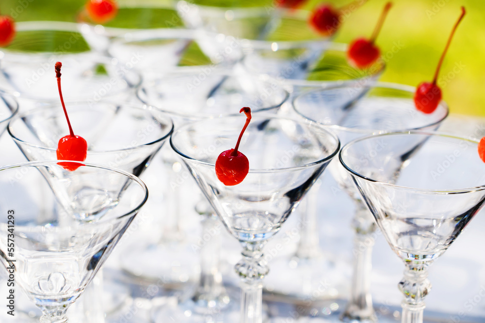 Obraz premium Cocktail glasses decorated with cherries. Preparation of alcoholic beverages at a party or holiday. selective focus