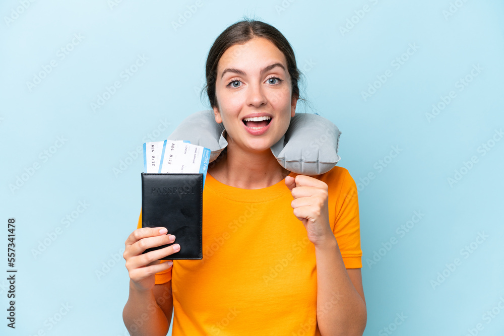 Young beautiful woman with Inflatable travel Pillow isolated on blue background celebrating a victory in winner position Young beautiful woman with Inflatable travel Pillow isolated on blue background celebrating a victory in winner position