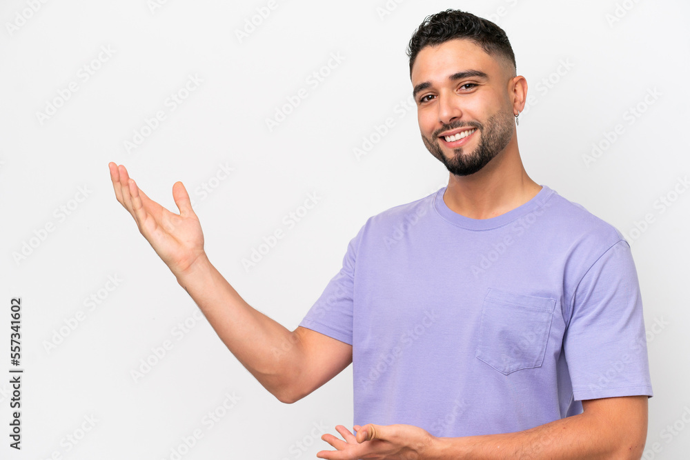Young Arab handsome man isolated on white background extending hands to the side for inviting to come Young Arab handsome man isolated on white background extending hands to the side for inviting to come