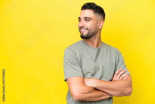 Young Arab handsome man isolated on yellow background looking to the side and smiling