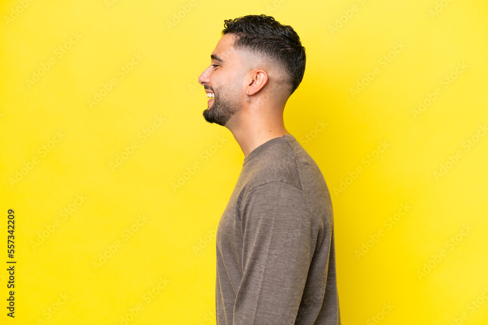 Young Arab handsome man isolated on yellow background laughing in lateral position Young Arab handsome man isolated on yellow background laughing in lateral position