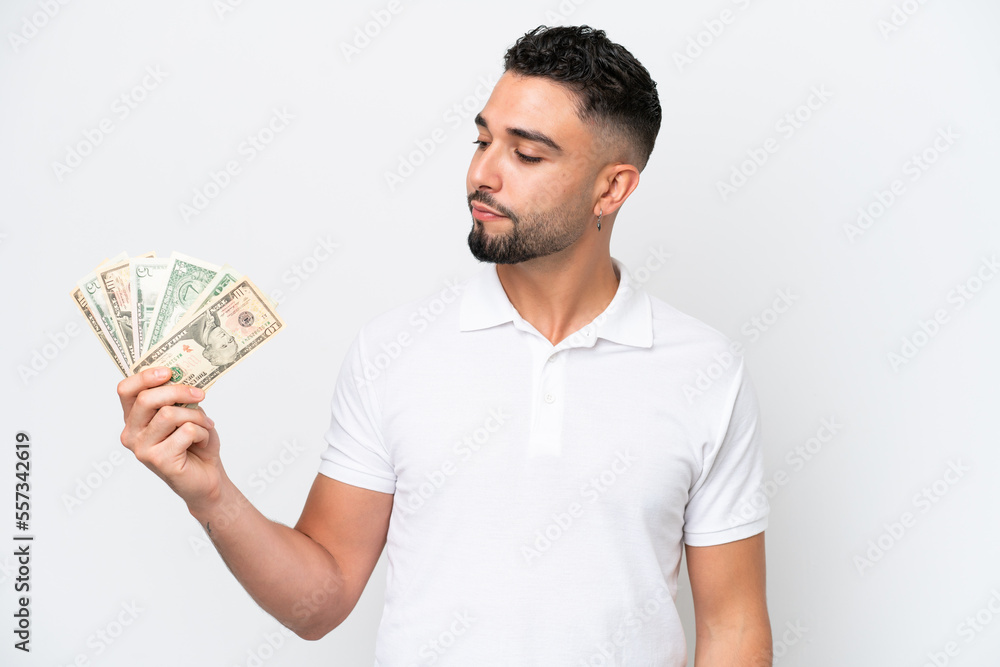 Young Arab man taking a lot of money isolated on white background looking to the side Young Arab man taking a lot of money isolated on white background looking to the side