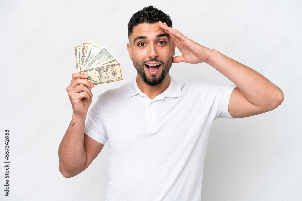 Young Arab man taking a lot of money isolated on white background with surprise expression Young Arab man taking a lot of money isolated on white background with surprise expression
