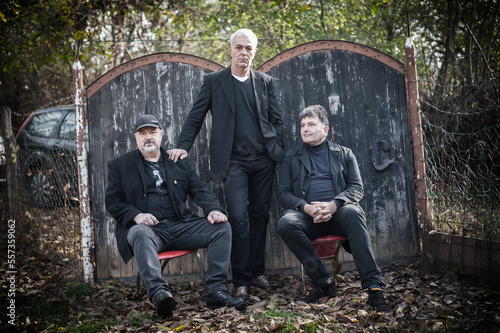 Bilde på lerret Group of three urban and handsome fashionable artist guys pose in black elegant