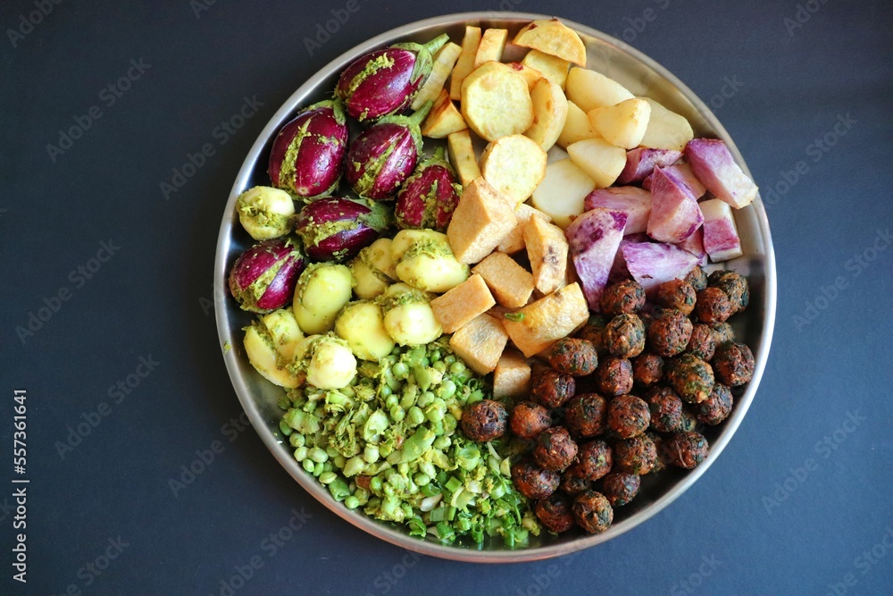 Mixed cut and marinated vegetables for Undhiyu. stuffed brinjals, fried potatoes, sweet potatoes, purple yam. preparation for surti undhiyu Indian Gujarati dish. Makar Sankranti Special Dish. Mixed cut and marinated vegetables for Undhiyu. stuffed brinjals, fried potatoes, sweet potatoes, purple yam. preparation for surti undhiyu Indian Gujarati dish. Makar Sankranti Special Dish.