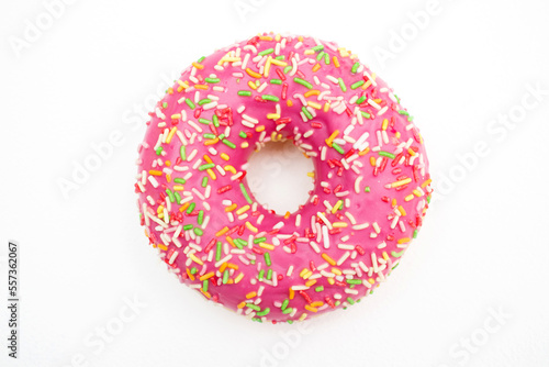 Pink donut decorated with colorful sprinkles isolated on white background.