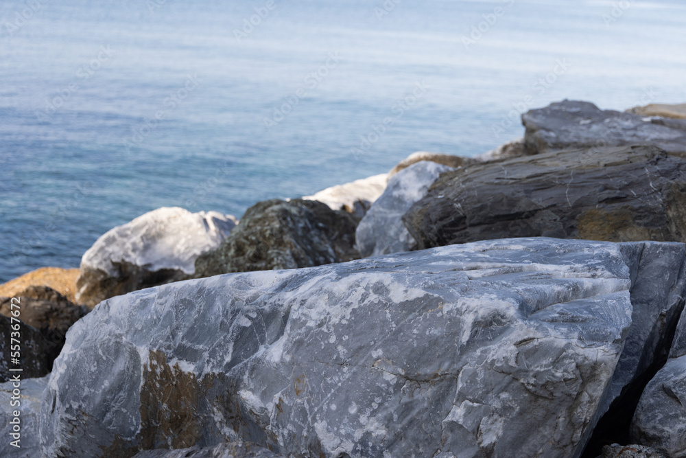 Close up of big stones of mediterranean sea shoe. Stone wave breakers of Italian coast on a sunny summer day. Genoa, region of Liguria, Italy.  Flat serene sea landscape.