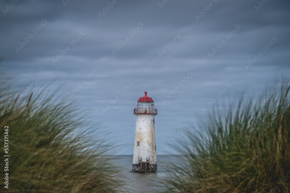 Lighthouse in a landscape photograph with blurred grasses in the foreground and a weathered battered lighthouse on a stormy day Lighthouse in a landscape photograph with blurred grasses in the foreground and a weathered battered lighthouse on a stormy day