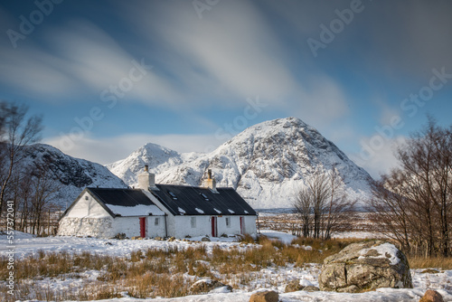 Old Cottage in the Scottish Highlands near Glencoe on a winters day with snow and mountains of Scotland covered in snow. Cold extreme Scottish weather. photo