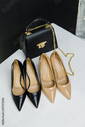 Elegant women's pumps with heels stand next to a black handbag on a white background. Place for writing