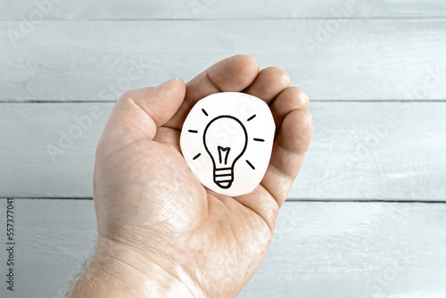 The man's hand is holding a light bulb icon. Concept of the idea. Energy Saving Concept