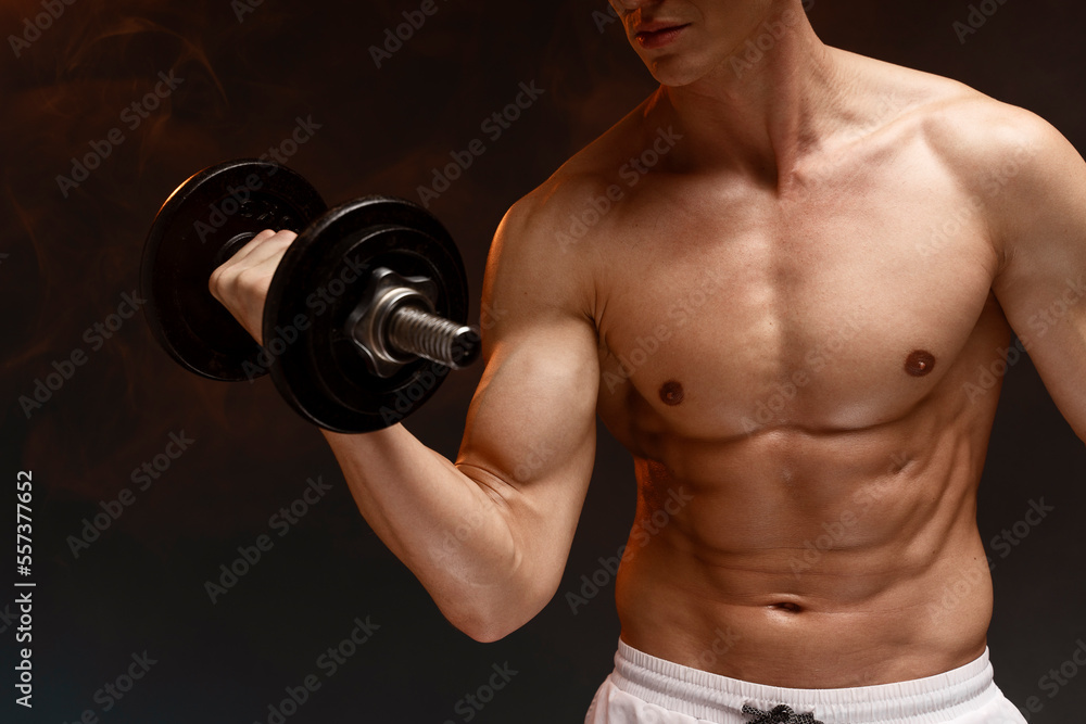 Naked man lifting dumbbell against black background. Strong people
