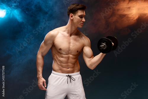 Sporty man with naked torso on black background. Athletic man doing exercises