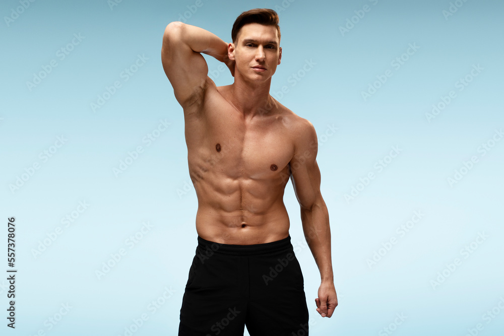Caucasian nude torso sexy man posing at studio over blue wall background