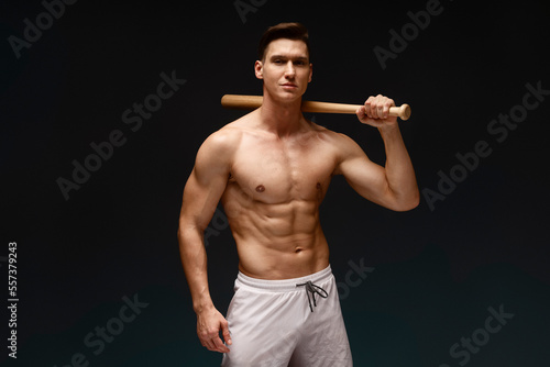 Canvas Print Close-up portrait of muscular man posing with bat at studio alone